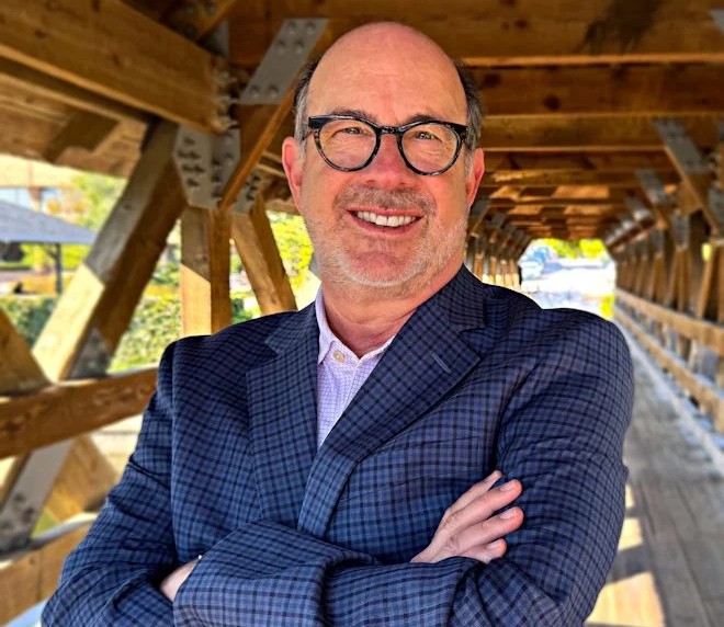 An image of the outgoing CEO of AfA, Brandon Fried. Smiling with his hands crossed.