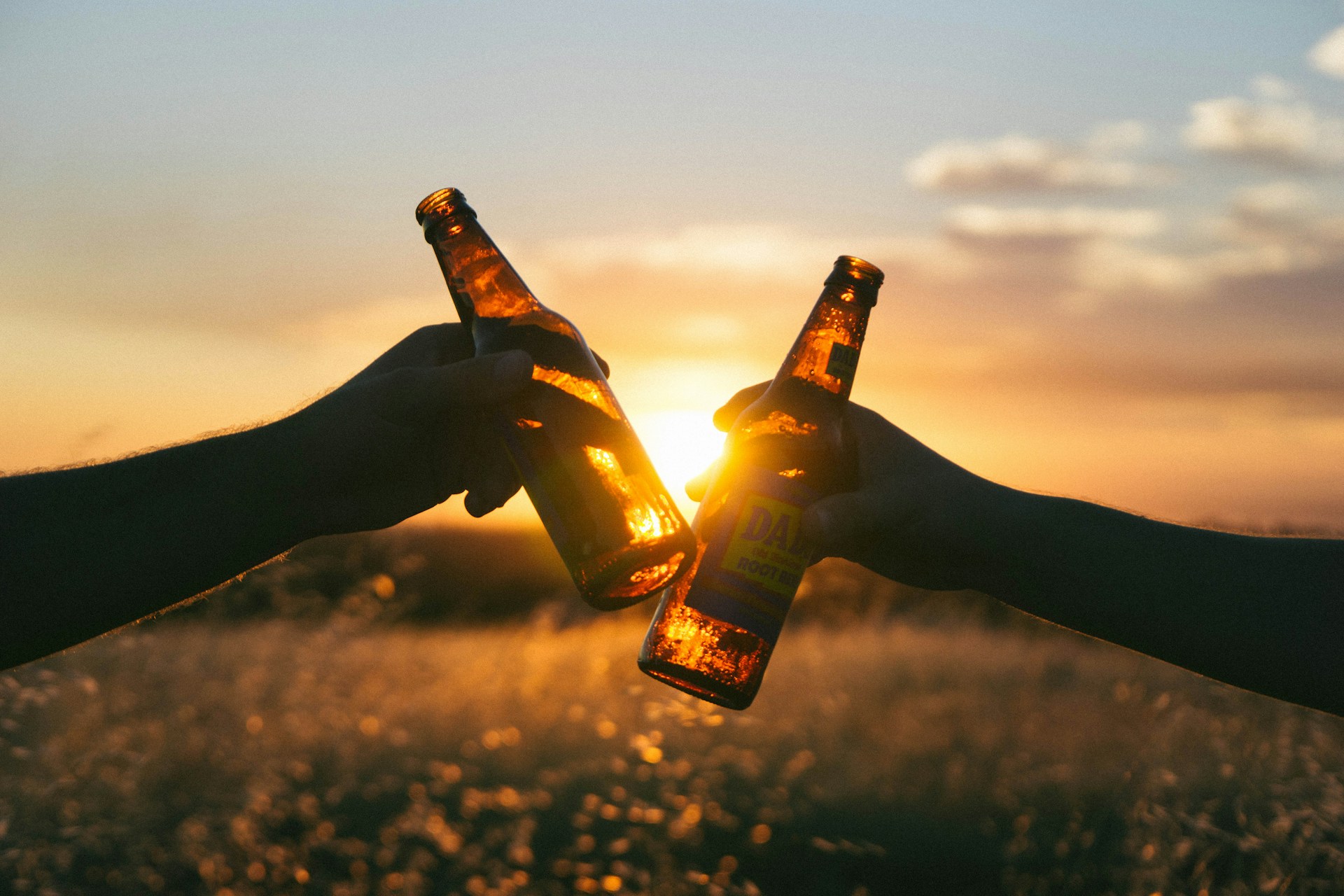 Two alcoholic drinks in a glass bottle with sunrise in the background 