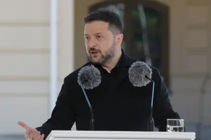 An image of Ukrainian President Volodymyr Zelensky giving an address with two microphones positioned in front of his face.