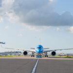 Airbus A350-900 on the runway before take-off, with a view of another aircraft taking off in the distance.