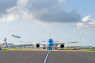 Airbus A350-900 on the runway before take-off, with a view of another aircraft taking off in the distance.