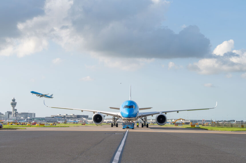 Airbus A350-900 on the runway before take-off, with a view of another aircraft taking off in the distance.