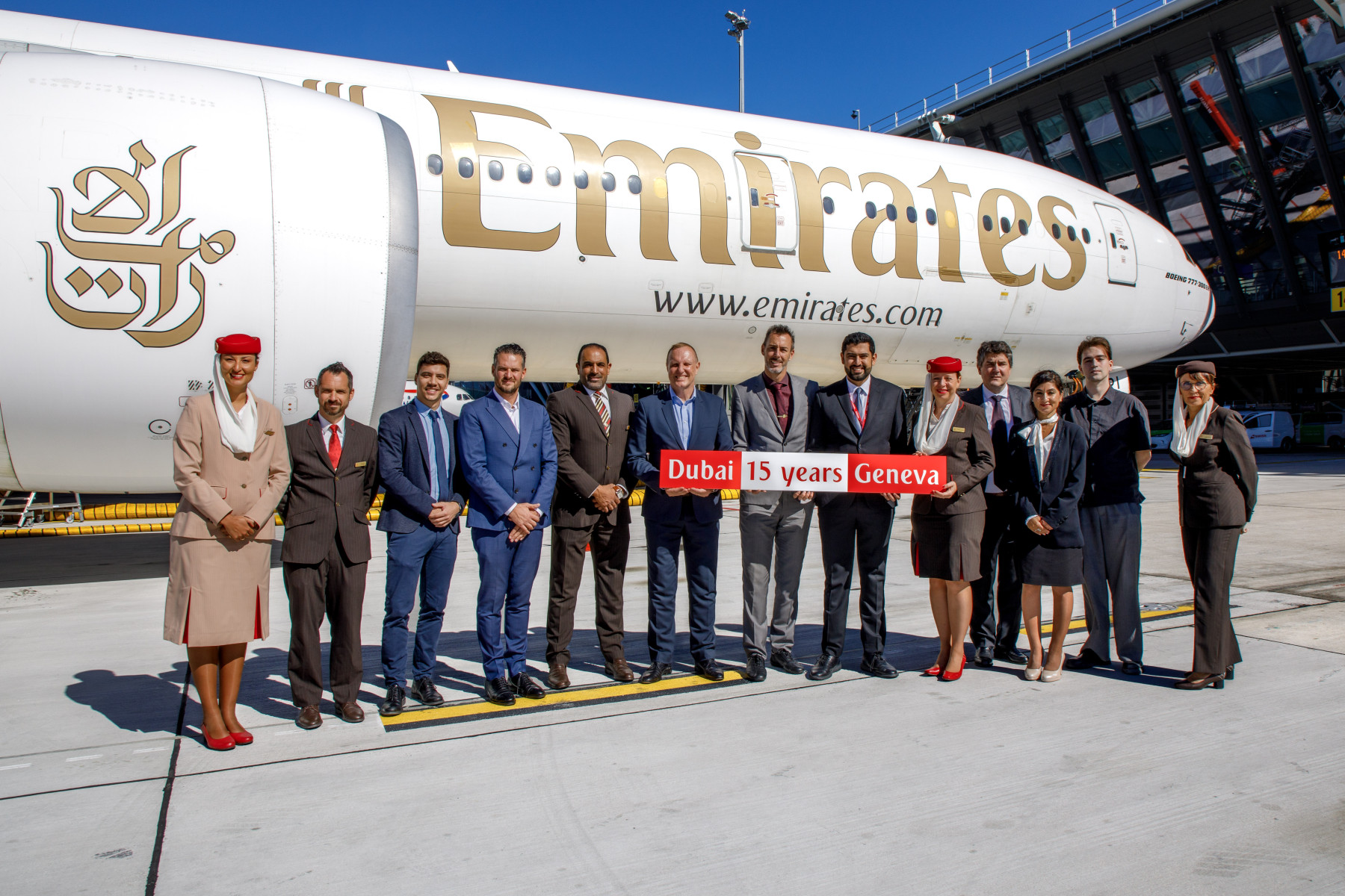 Photograph depicting an Emirates airplane surrounded by Emirates staff members on the runway to mark 15 years of flights between Dubai and Geneva. 
