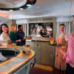 Photograph depicting Emirates passengers enjoying Dubai+ at the first and business class onboard lounge - a dedicated selection of Emirati and regional entertainment available through the airline’s award-winning ice inflight entertainment system.