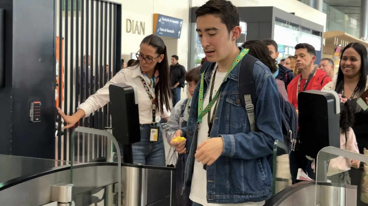Photograph depicting an individual with Autism wearing a sunflower lanyard walking through the gates during the Emirates travel rehearsal in a Colombia airport.