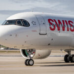 Photograph depicting the front aspect of SWISS A320 Neo aircraft, including a view of the cockpit and wheels, when the aircraft is on the airport runway.
