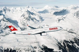 Photograph depicting a SWISS Airbus A330-300 flying above a snowy and mountainous landscape.