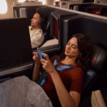 Two people on a Delta flight sitting in Delta One premium seats.