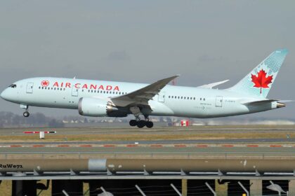 Air Canada Boeing 787-8 Dreamliner taking off, nose wheel raised, with a red maple leaf on a pale turquoise tail, seen above a fence and runway.