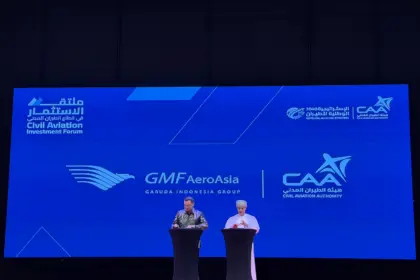 Photo of a presentation between President of Oman's CAA and AeroAsia's CEO (right to left) with a large board behind titled "GMF AeroAsia Garuda Indonesia Group".