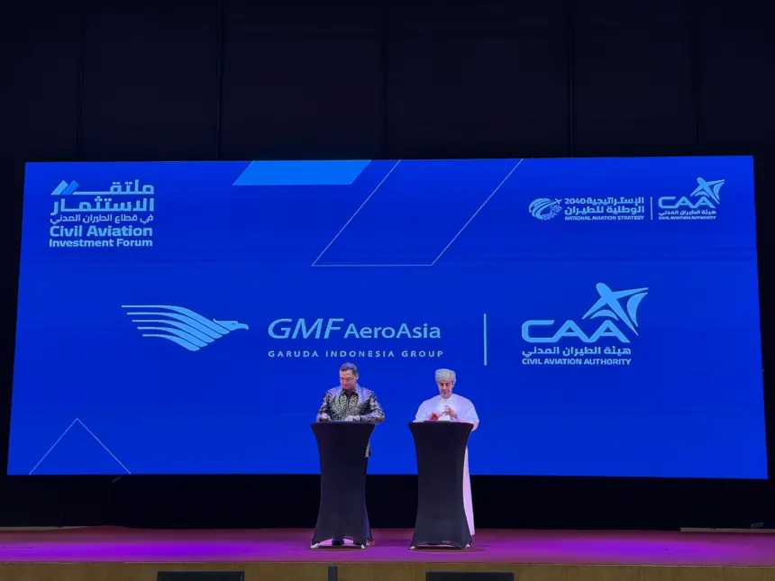Photo of a presentation between President of Oman's CAA and AeroAsia's CEO (right to left) with a large board behind titled "GMF AeroAsia Garuda Indonesia Group".