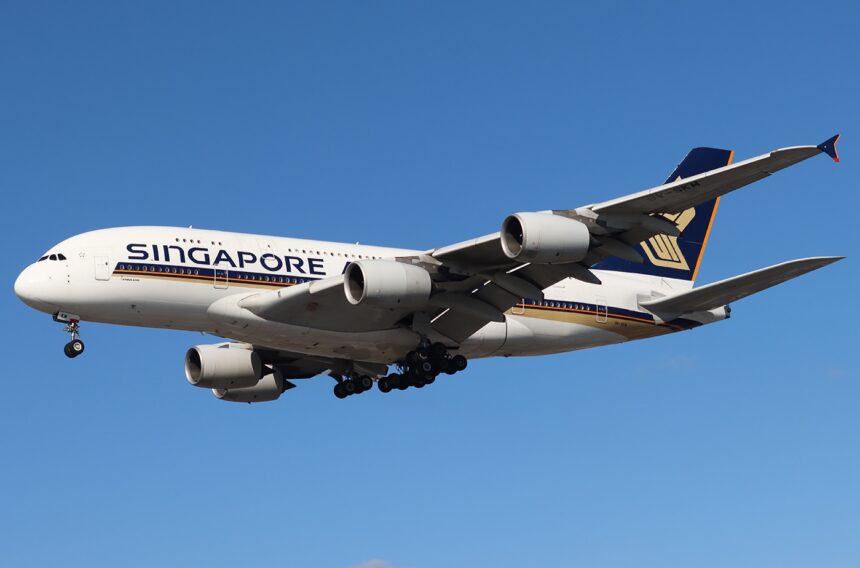 A Singapore Airlines Airbus A380-841 in the air, against a clear blue sky.