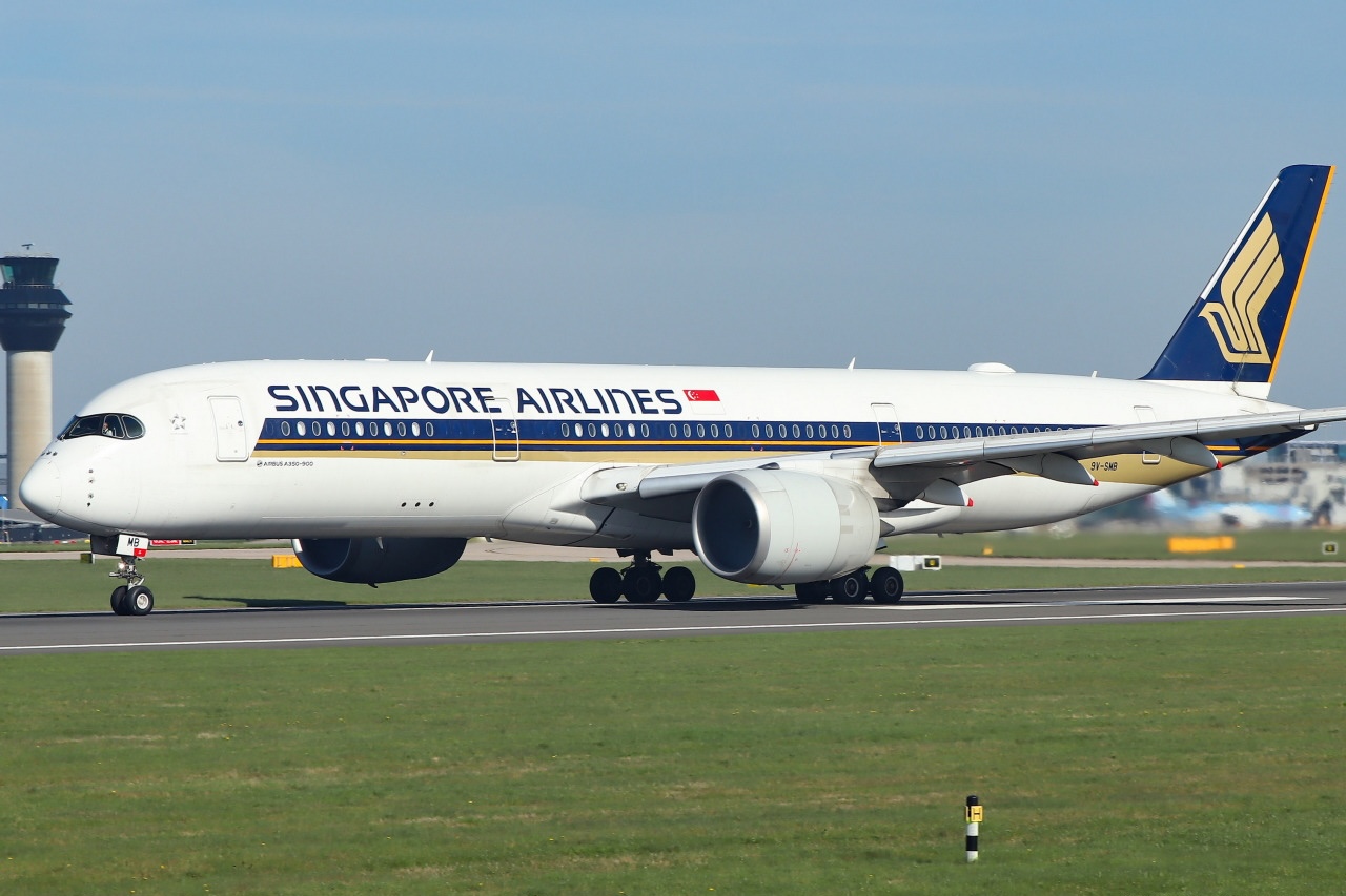 A Singapore Airlines Airbus A350-941 wide-body commercial airliner is pictured taxiing at an airport. A clear blue sky and air traffic control tower can be seen in the background.