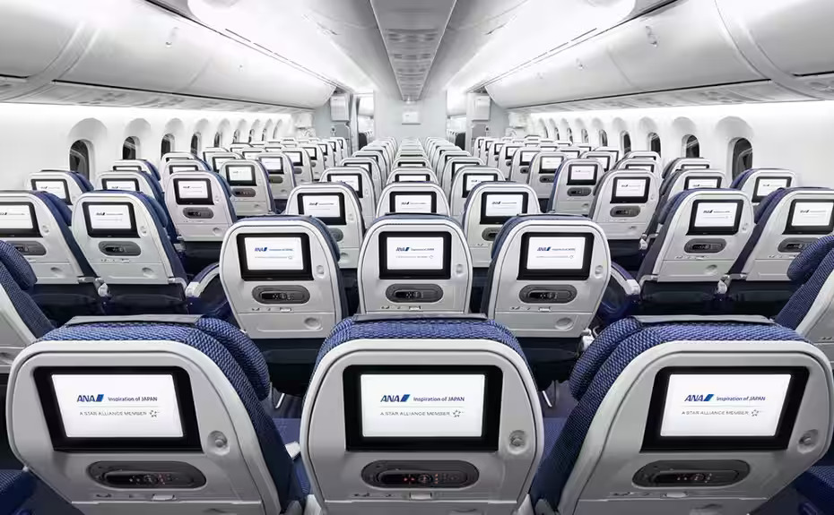 Photograph depicting interior of ANA All Nippon Airways Economy Class cabin featuring comfortable seats and in-flight entertainment screens.