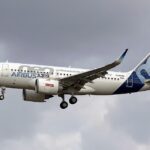 Image shows an Airbus aircraft in flight on a cloudy day