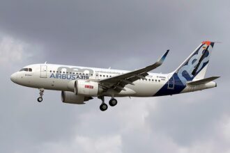 Image shows an Airbus aircraft in flight on a cloudy day