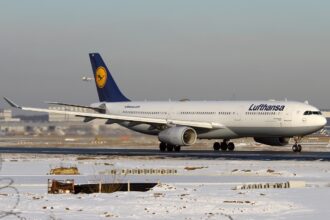 A wintery day featuring a Lufthansa Airbus A330-343X on the runway in Frankfurt Airport. The ground is white with lightly dusted snow and the classic Lufthansa colours of white, yellow and navy can be seen.