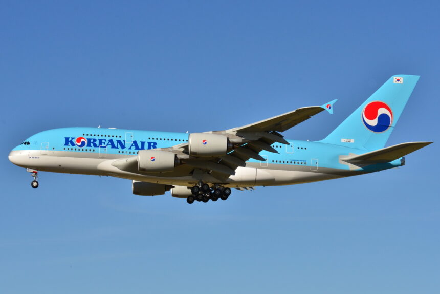 A aircraft with blue fuselage flying against a blue, clear sky