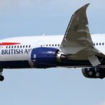 Head of a British Airways Boeing 787-8 Dreamliner in the sky with its landing gear still extended.