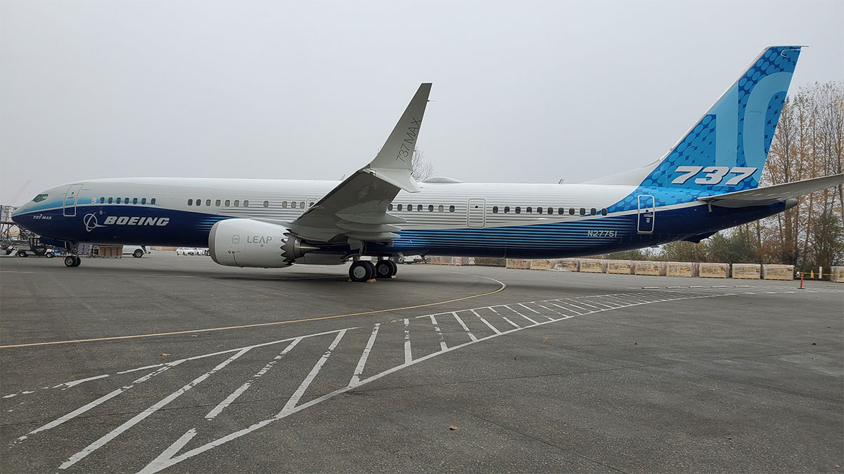 A Boeing 737 MAX 10 airplane parked on an asphalt tarmac, featuring a white and blue livery with the Boeing logo and 737 branding on the tail section.