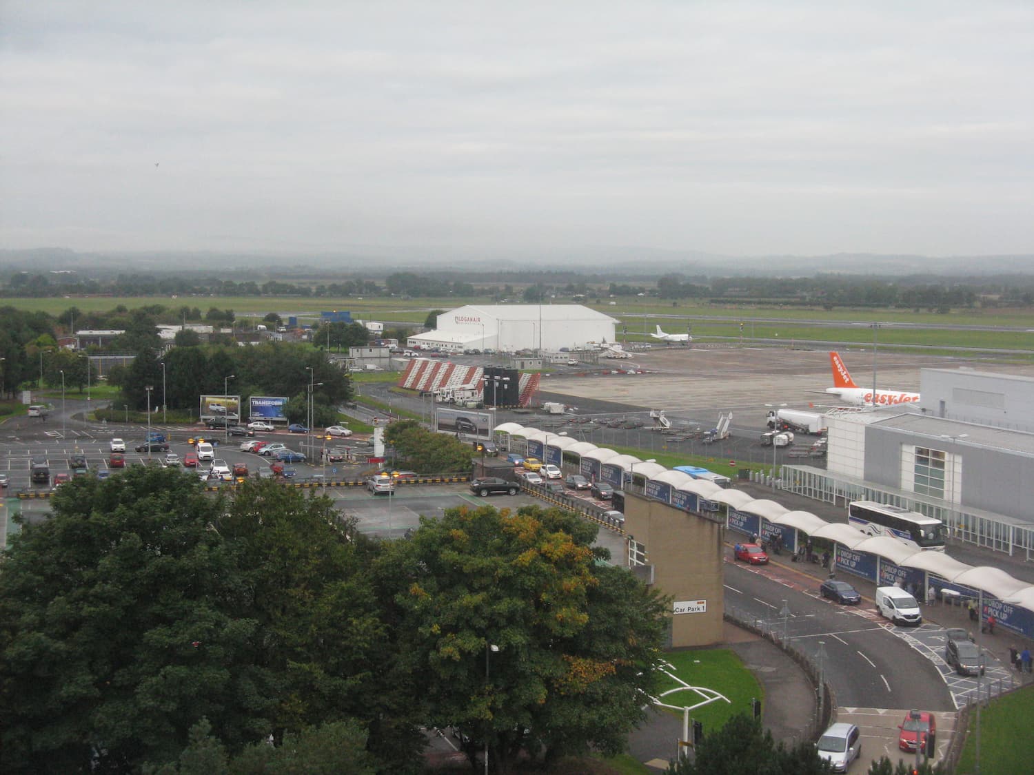 Image shows Glasgow Airport's drop off point with the runway in the background
