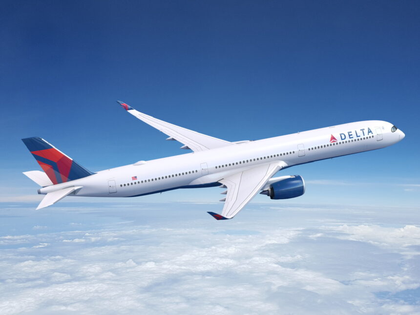A white and red Delta Air Lines Airbus jet flying above a layer of cloud in front of a dark blue sky.