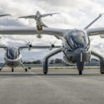 Two Archer Midnight aircraft sat on an airport runway in front of a cloudy sky.