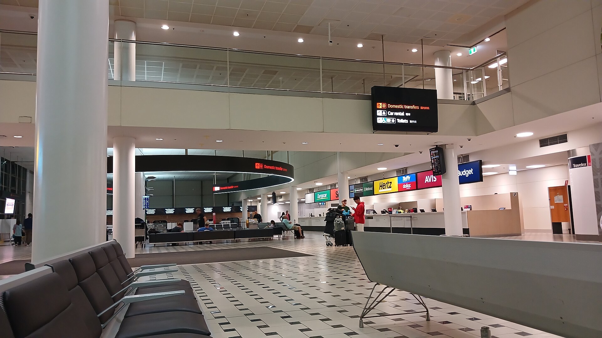 The terminal at Brisbane Airport (BNE). Some chairs are shown in a well-lit but empty hall.