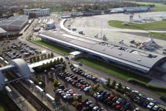 An aerial view of London Southend Airport (SEN). A car park is shown on one side of the airport terminal, with runways and grassy areas on the other.