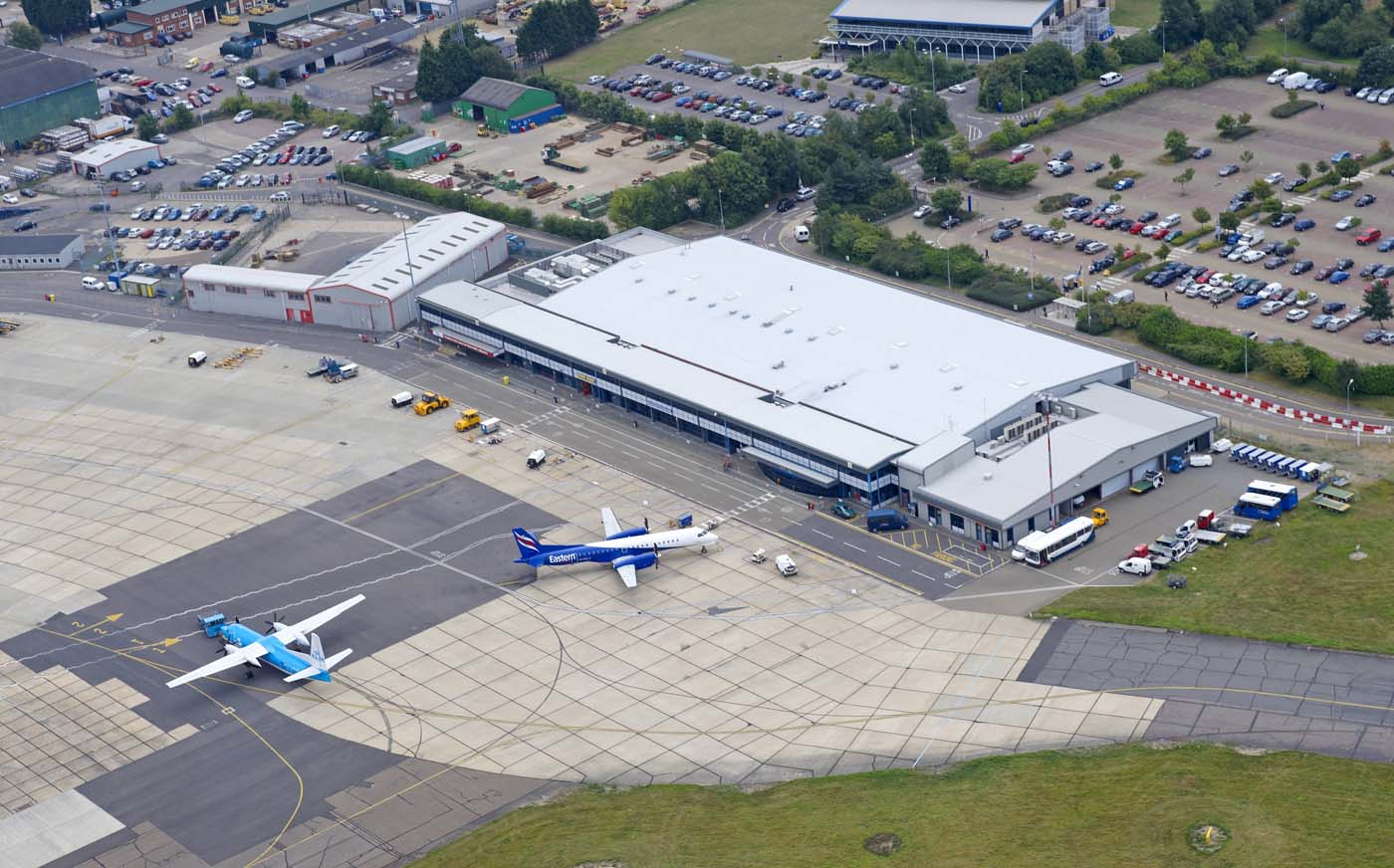 An aerial view of Norwich Airport (NWI). Two jets are shown outside the airport terminal.