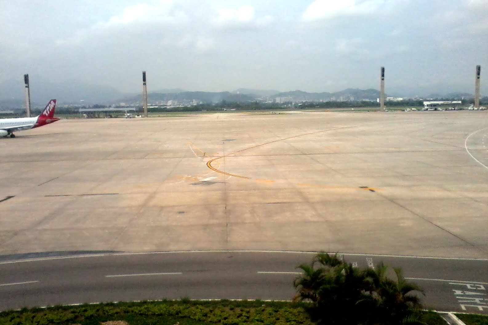 A grey runway at Rio de Janeiro/ Galeao-Antonio Carlos Jobim International Airport (GIG) in front of a cloudy sky.