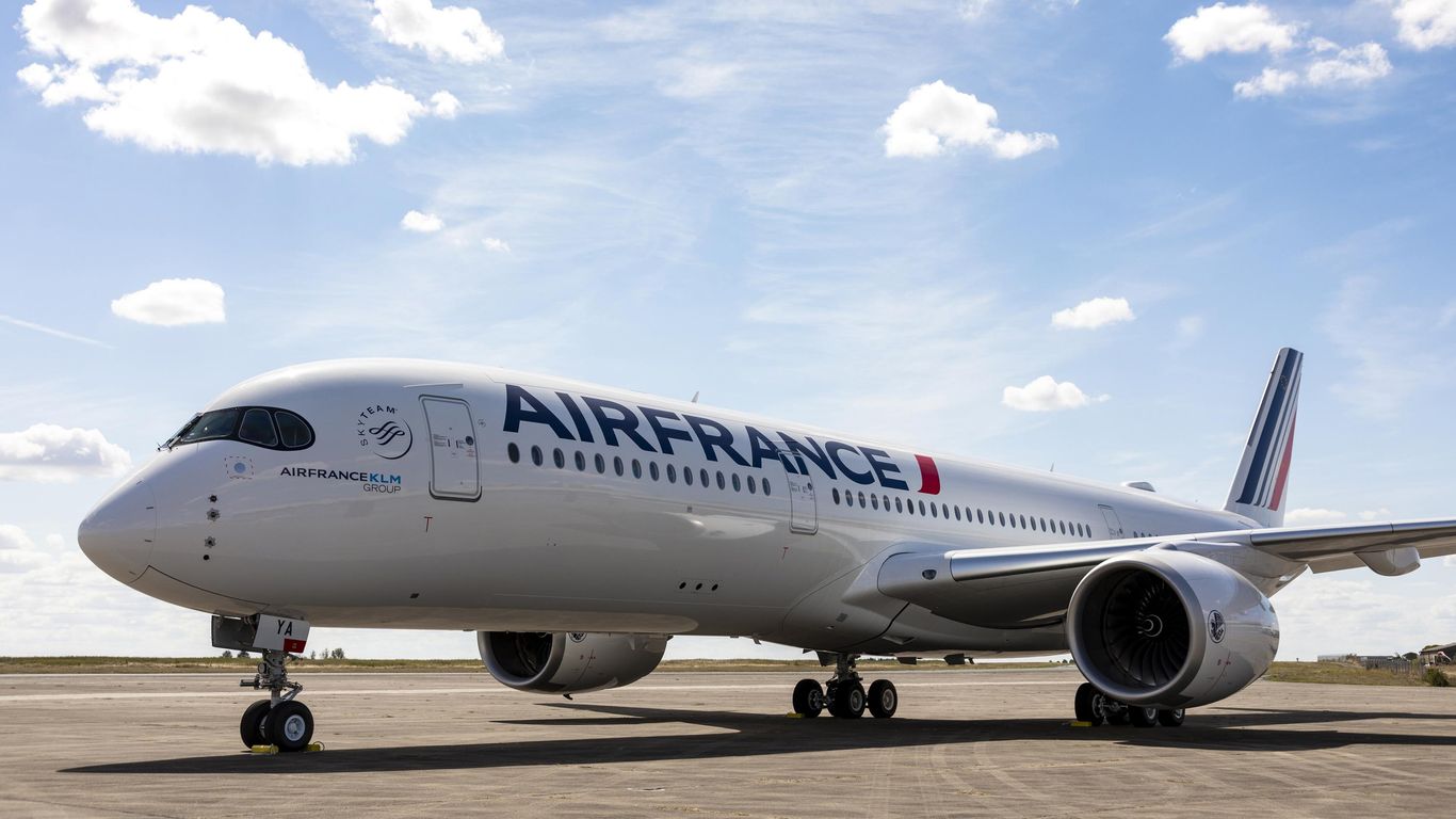 A white and blue Air France jet parked on a runway in front of a cloudy sky.