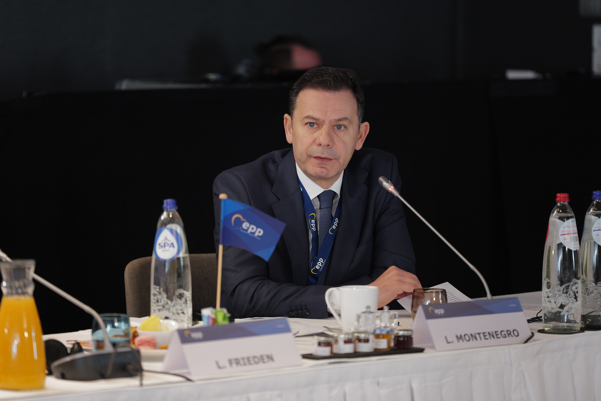 Portuguese Prime Minister Luis Montenegro sat at a white table behind a microphone.