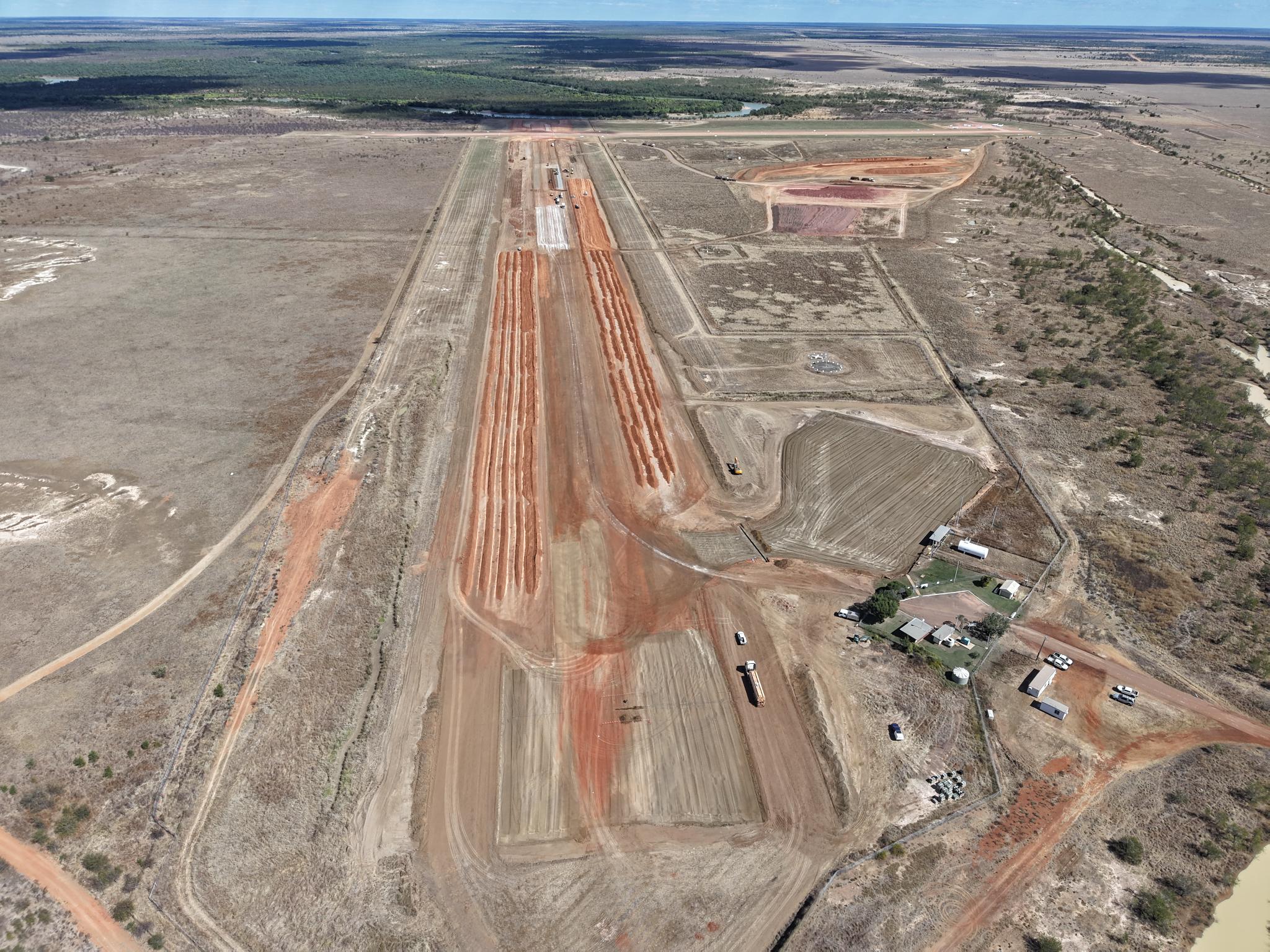 An aerial Burketown Airport in Queensland. Orange gravel tracks are being used as runways, amid a sandy landscape.
