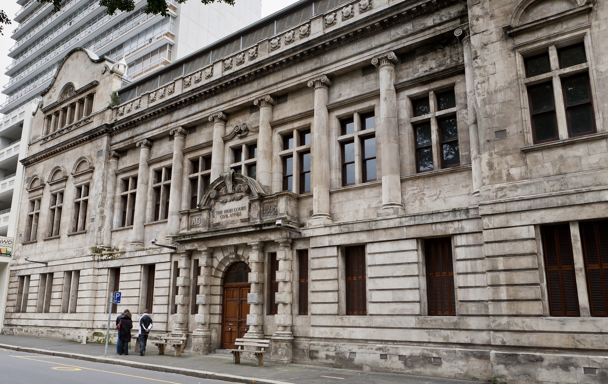 The grey, stony exterior of Western Cape High Court in Cape Town, South Africa. A wooden door is visible in the centre of the stone wall.