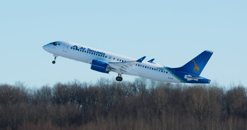 A blue and white Air Tanzania jet taking off in front of a row of trees.