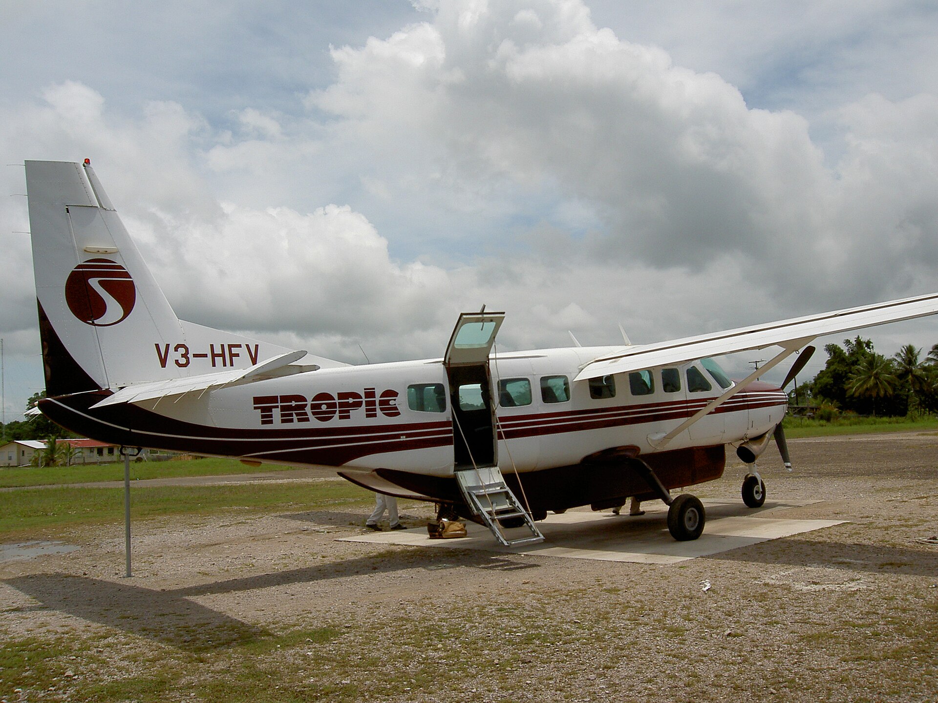 A red and white Tropic Air plane sat on a runway on a cloudy day.