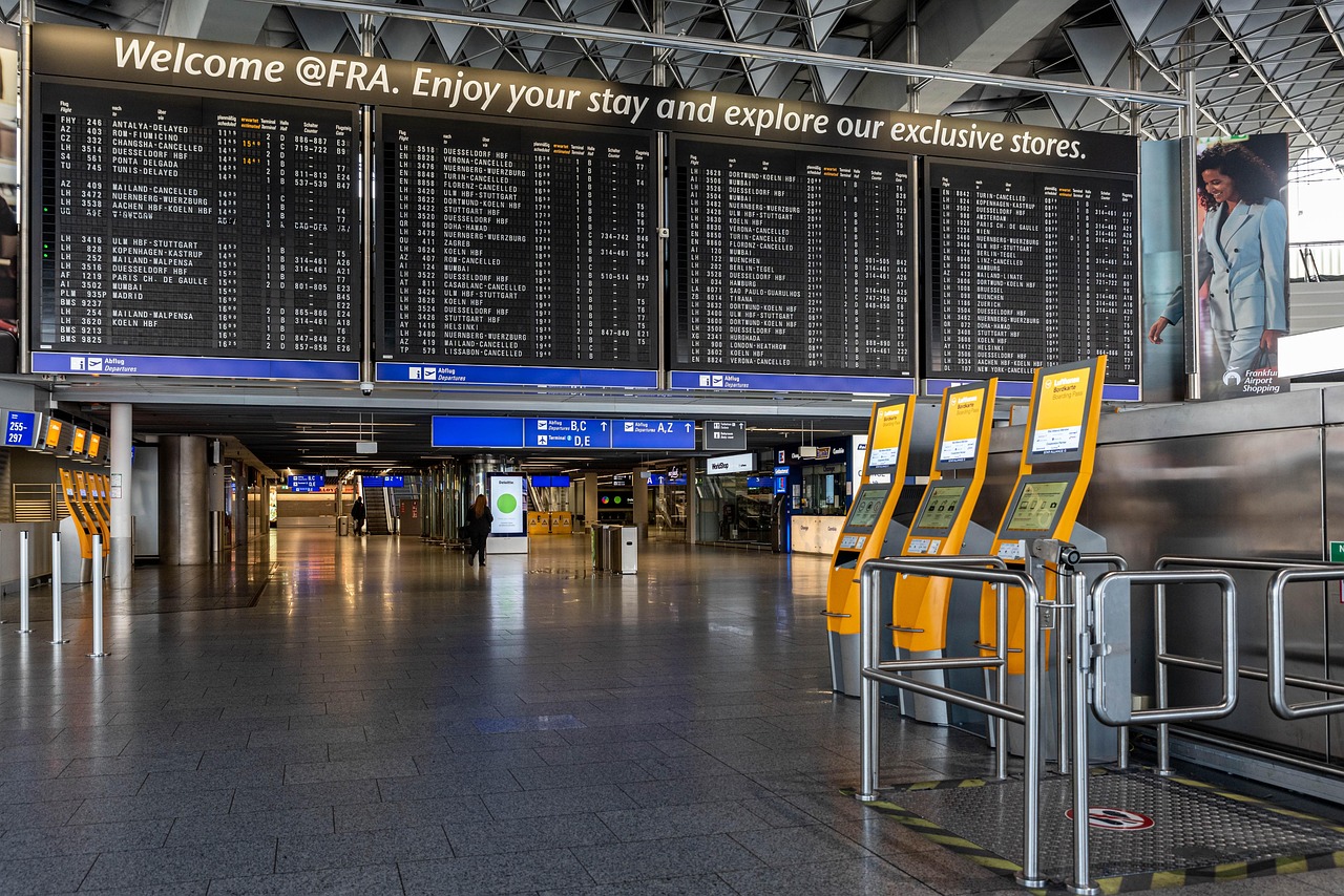 An empty airport terminal, showing a list of upcoming flights on overhead screens.