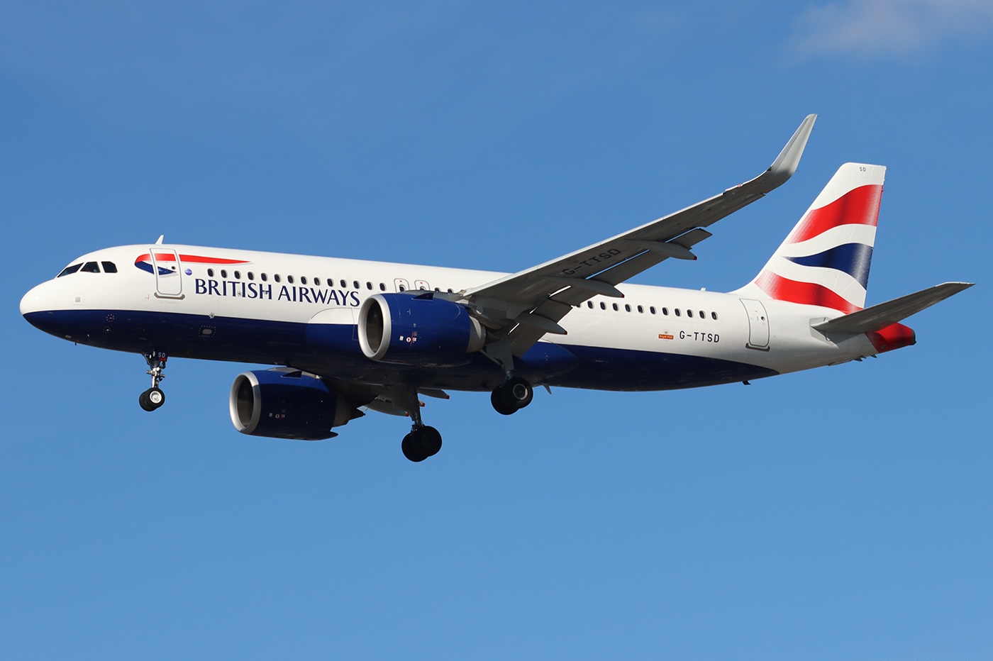 Full body of a British Airways Airbus A320-232 in the sky with its landing gear still extended.