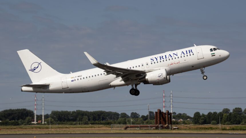 Syrian Air Airbus A320 climbs after take-off with landing gear extended, flying above a runway under a clear blue-grey sky.