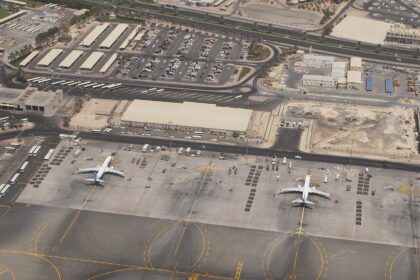 An outside aerial image of Mumbai International Airport, Terminal 2. The surroundings are dull and dry with a few airplanes dotted along the outside.