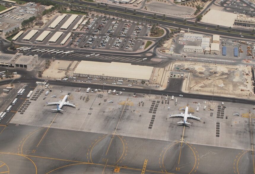 An outside aerial image of Mumbai International Airport, Terminal 2. The surroundings are dull and dry with a few airplanes dotted along the outside.
