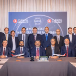 Group of delegates posing behind a conference table in front of a Turkish Airlines, CFM and Turkish Technic backdrop.