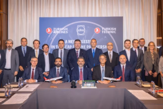 Group of delegates posing behind a conference table in front of a Turkish Airlines, CFM and Turkish Technic backdrop.
