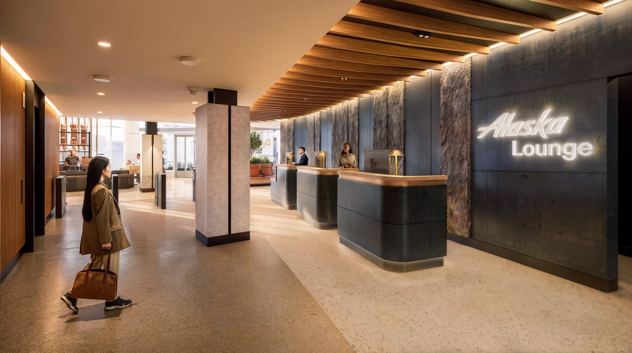 The new Alaska Air lounges for premium class have deep brown wood details mixed with warm sandy colours and more beige wooden panelling. Warm, inviting lighting greets the woman who is carrying her bag to the check-in desk.