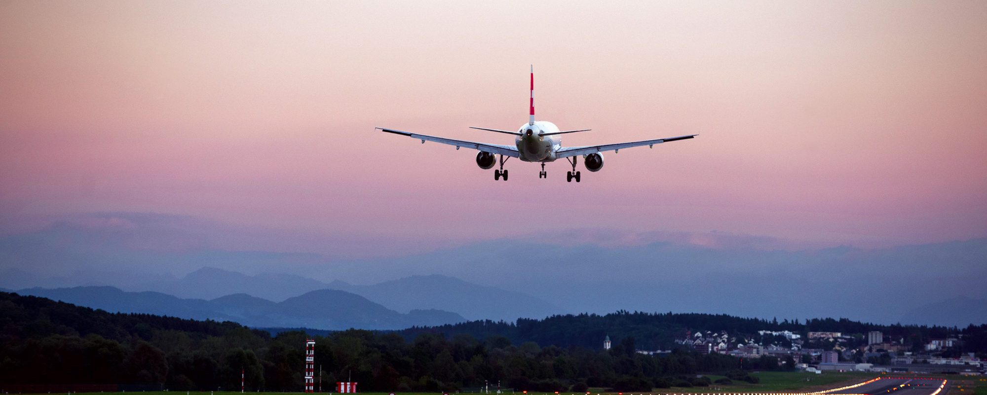 Photograph depicting a SWISS aircraft flying above the surrounding landscape after take-off from the runway.