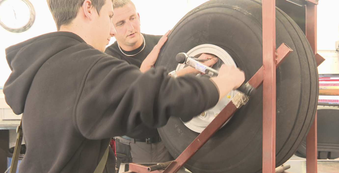 Dmytro Miskov working on a wheel of an aircraft whilst being supervised by a member of Loganair's mechanic team.