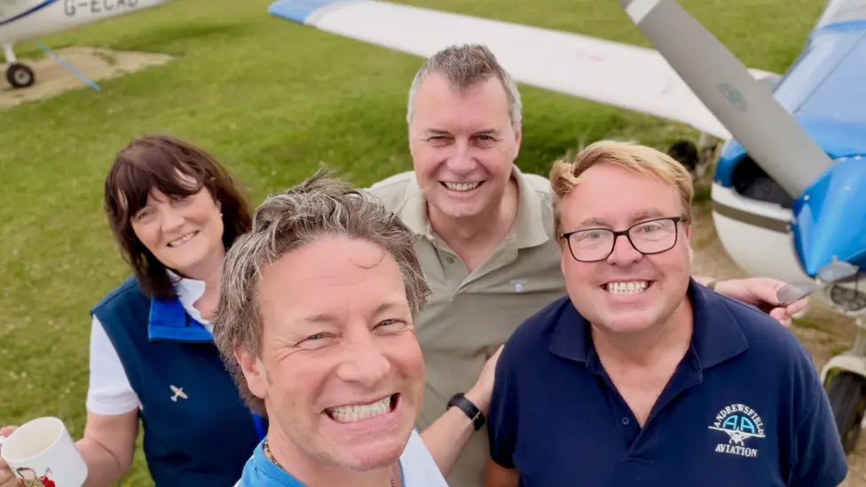 (Left to right) Head of training Carol Cooper, Jamie Oliver, flight instructor Mick Pitcher and Marc "Blondie" Naylor. They are all smiling alongside a small aircraft.