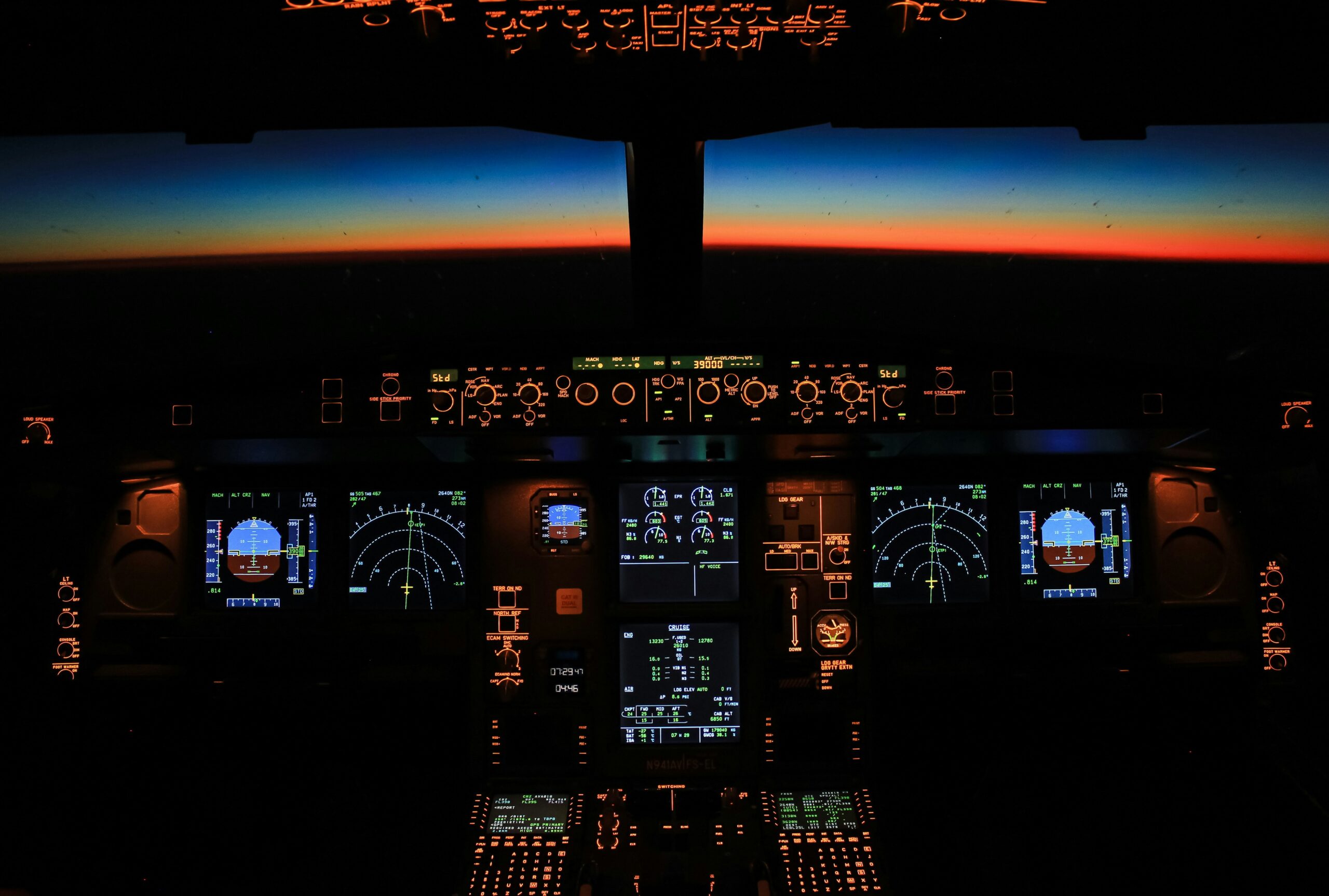 The cockpit of an aircraft which lights up with a sunset visible through the cockpit windscreen.