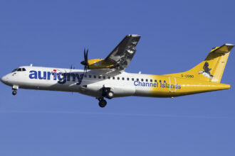 An Aurigny Air Services plane ascending into a bright blue sky.